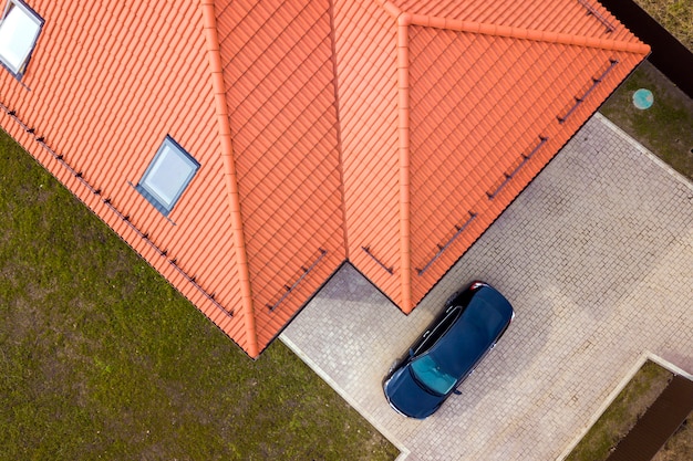 Luchtfoto van huis met zolderramen en zwarte auto op verharde tuin