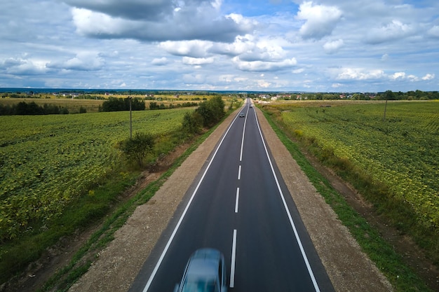 Luchtfoto van intercityweg tussen groene landbouwvelden met snel rijdende auto's Bovenaanzicht van drone van snelwegverkeer