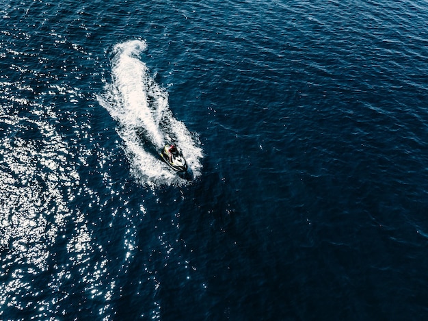 Luchtfoto van jetskiër in blauwe zee jetski in turkoois helder water racen op hoge snelheid