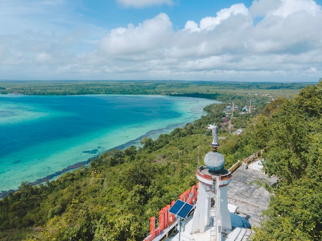 Luchtfoto van Jezus standbeeld met prachtig uitzicht op het strand in klein eiland. Maluku, Indonesië - juli 2022