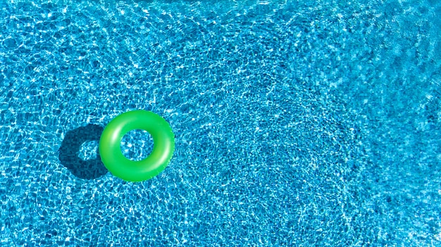 Luchtfoto van kleurrijke opblaasbare ring donut speelgoed in zwembad water van bovenaf, familievakantie concept achtergrond