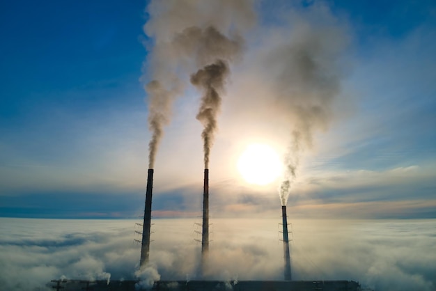 Foto luchtfoto van kolencentrale hoge pijpen met zwarte rook vervuilende atmosfeer verplaatsen bij zonsondergang