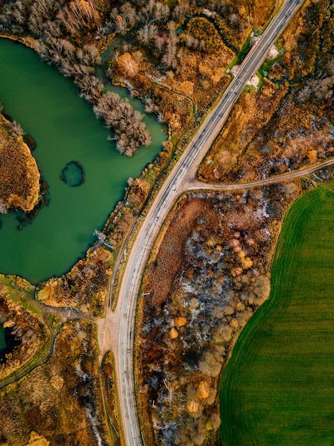 Foto luchtfoto van kronkelende rivier en weg in goudkleurig herfst- of herfstbos