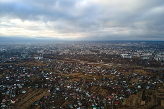 Luchtfoto van landelijke huizen en verre hoge flatgebouwen in de woonwijk van de stad tijdens bewolkt weer