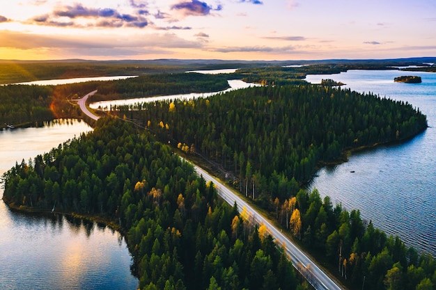 Luchtfoto van landweg in groen zomerbos met blauwe meren bij zonsondergang in finland