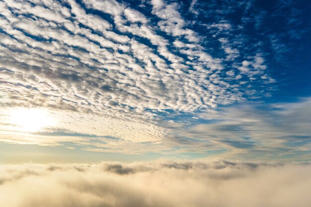 Luchtfoto van levendige gele zonsopgang boven witte dichte wolken met blauwe lucht boven je hoofd.