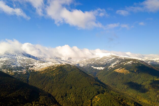 Luchtfoto van majestueuze bergen bedekt met groen sparrenbos en hoge besneeuwde toppen.