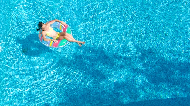 Luchtfoto van meisje in zwembad van bovenaf, kind zwemmen op opblaasbare ring donut en heeft plezier in het water op familievakantie