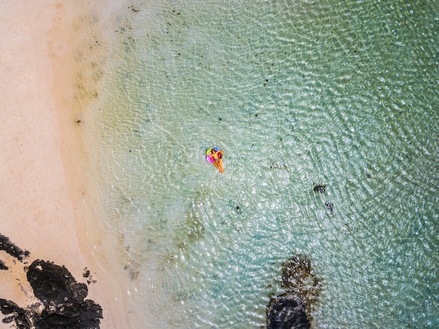 Luchtfoto van mensen in zomervakantie vakantie met mooi meisje op gekleurde trendy lilo ontspannen en zonnebaden op helder groen oceaan lagune strand water