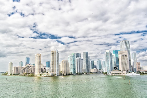 Luchtfoto van miami wolkenkrabbers met blauwe bewolkte hemel, witte boot zeilen naast het centrum van miami