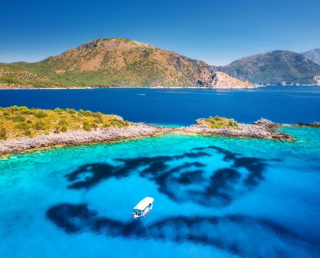 Luchtfoto van mooi alleen jacht op zee bij zonsondergang in de zomer Akvaryum koyu in Turkije Bovenaanzicht van boten op helderblauw water rotshemel berg en groene bomen Reizen en natuur Landschap