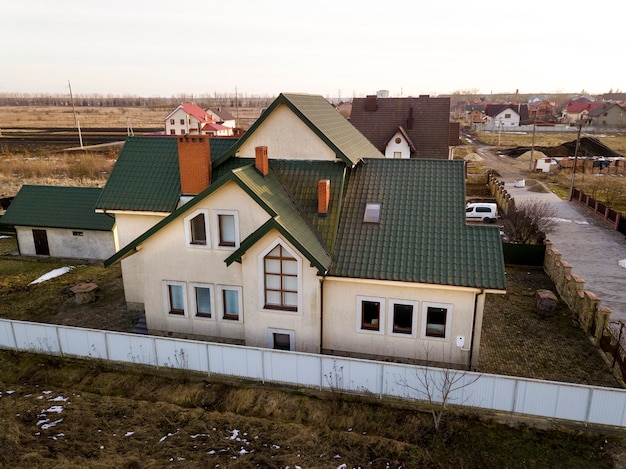 Luchtfoto van nieuwe woonhuis cottage en garage of schuur met shingledak op omheinde tuin op zonnige dag.