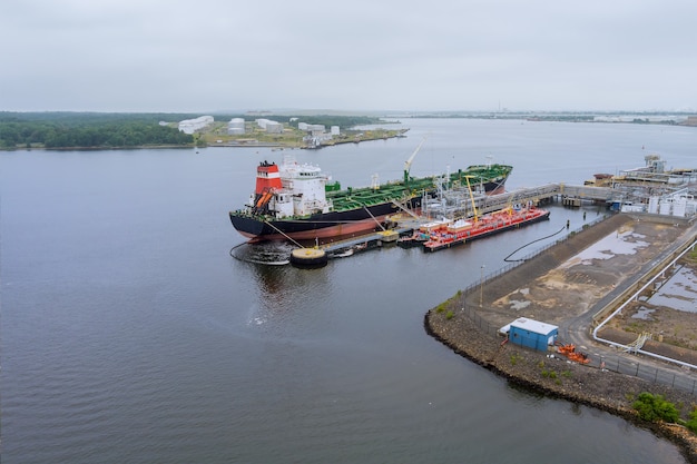 Luchtfoto van olietankerschip afgemeerd aan een olieopslagterminal in de haven