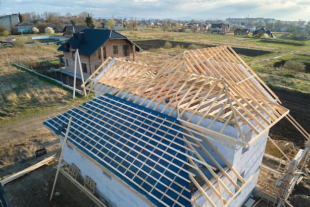Luchtfoto van onafgewerkt frame van woonhuis met beluchte lichtgewicht betonnen muren en houten dakframe in aanbouw.