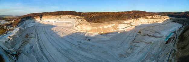 Foto luchtfoto van open pit mining site van kalksteen materialen voor de bouwsector met graafmachines en dump trucks.