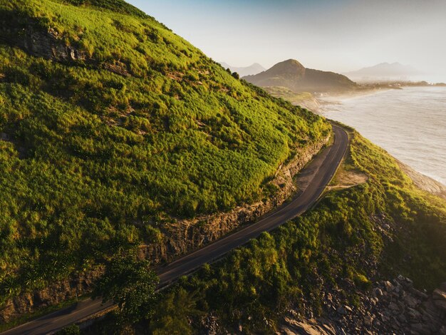 Luchtfoto van Prainha Beach, in Rio de Janeiro, Brazilië. Grote heuvels rondom. Zonnige dag bij dageraad. Groenachtige zee. Drone foto. Straat die twee stranden met elkaar verbindt. Recreio dos Bandeirantes op de achtergrond.