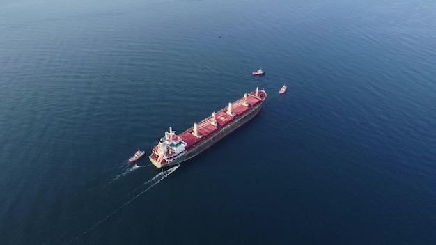 Luchtfoto van sleepboot die groot bulkcarriervrachtschip assisteert Groot schip geëscorteerd door sleepboot