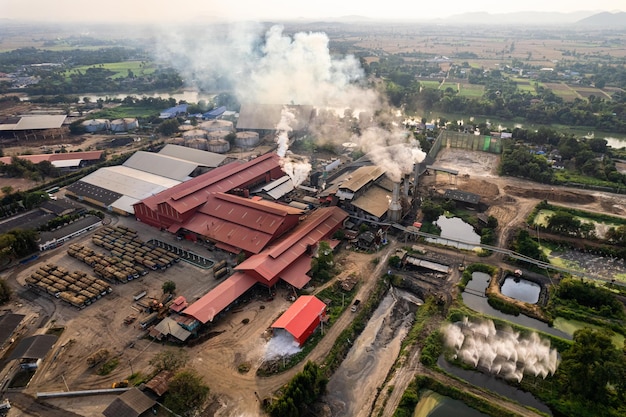 Luchtfoto van suikerbio-ethanol vertaalfabriek die werkt met stoom uit de schoorsteen en suikerrietwagen