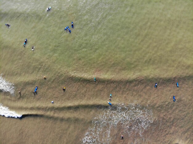 Luchtfoto van surfers die wachten op de golven in het donkerbruine water