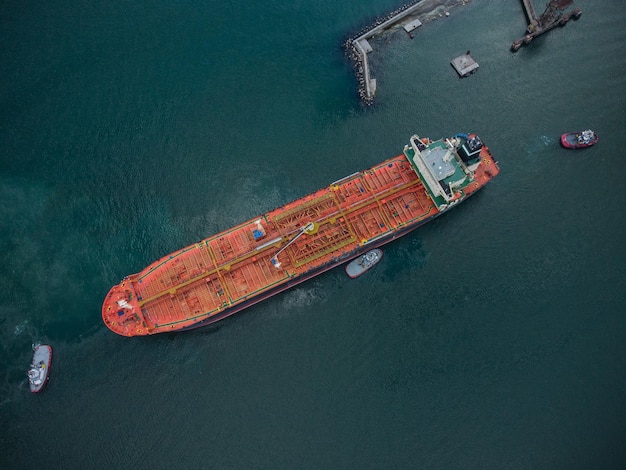 Luchtfoto van tankschip met begeleidende sleepboot die de haven verlaat