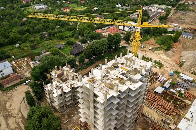 Luchtfoto van toren hijskraan en betonnen frame van hoge flat residentiële gebouwen in aanbouw in een stad.