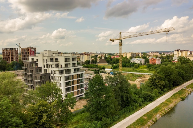 Luchtfoto van toren hijskraan en betonnen frame van hoog flatgebouw in aanbouw in een stad.