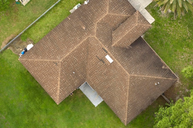 Luchtfoto van typisch eigentijds Amerikaans privéhuis met dak bedekt met asfaltshingles en groen gazon op de werf