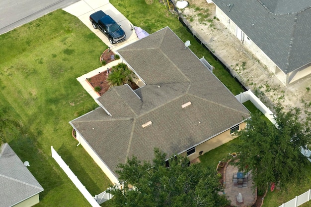 Luchtfoto van typisch eigentijds Amerikaans privéhuis met dak bedekt met asfaltshingles en groen gazon op de werf