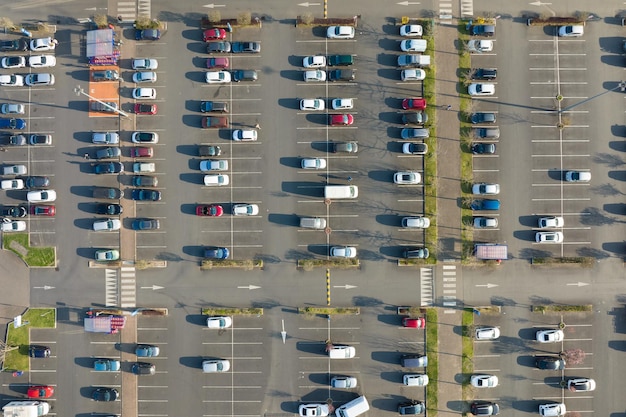 Luchtfoto van veel kleurrijke auto's geparkeerd op parkeerplaats met lijnen en markeringen voor parkeerplaatsen en richtingen