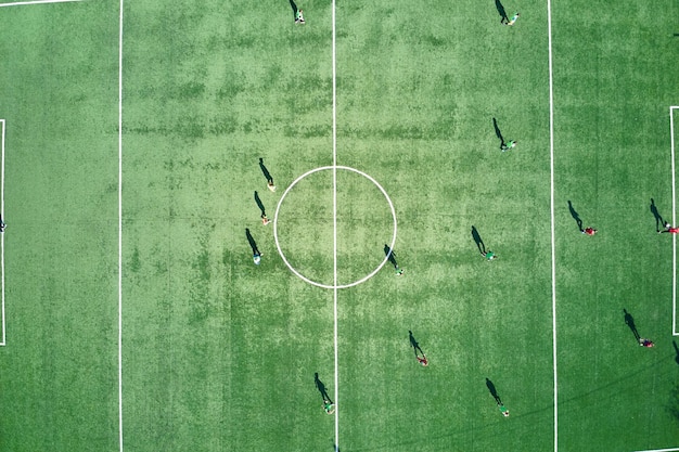 Luchtfoto van voetballers die voetbal spelen op groen sportstadion