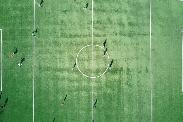 Luchtfoto van voetballers die voetballen op groen sportstadion.
