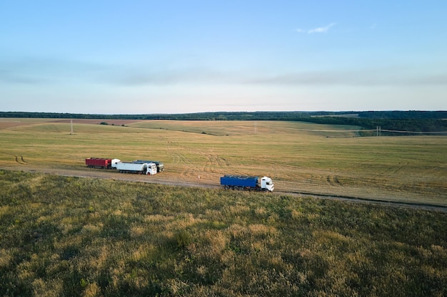 Luchtfoto van vrachtauto rijden op onverharde weg tussen landbouwtarwevelden die veel stof maken Transport van graan na te zijn geoogst door maaidorser tijdens het oogstseizoen