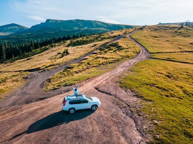 Luchtfoto van vrouw zittend op het dak van suv auto genieten van het uitzicht. rondrit. zomer. Dragobrat Karpaten in Oekraïne