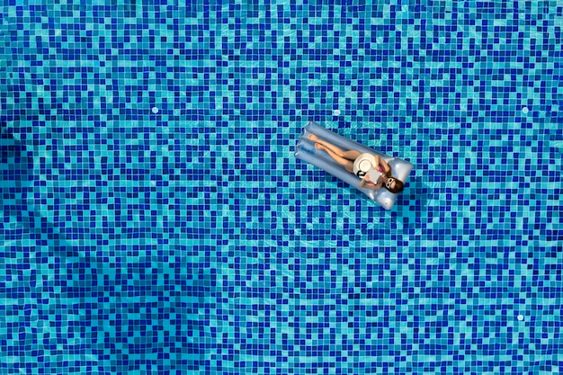 Luchtfoto van vrouwen drijvend op opblaasbaar over blauw zwembad