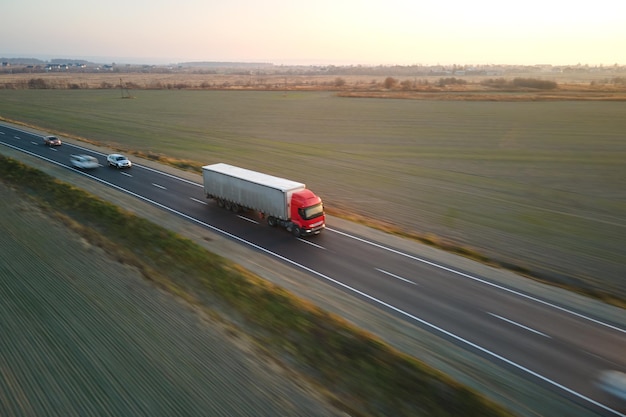 Luchtfoto van wazig snel bewegende semi-vrachtwagen met vrachtaanhangwagen rijden op snelweg goederen vervoeren in de avond. levering transport en logistiek concept