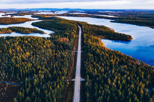 Luchtfoto van weg door herfstbos met blauwe meren in Finland Lapland