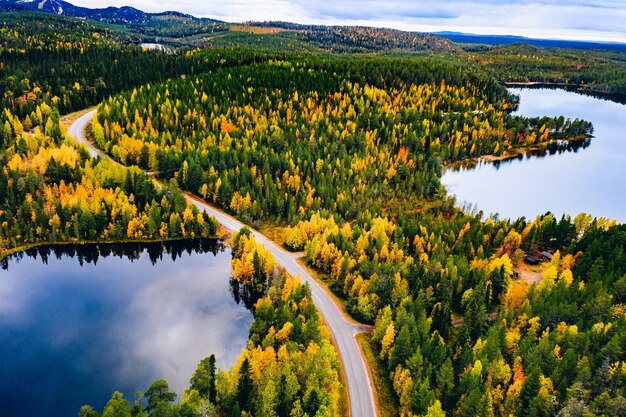 Luchtfoto van weg en kleurrijk herfstbos met bergen en blauwe meren in Finland Lapland