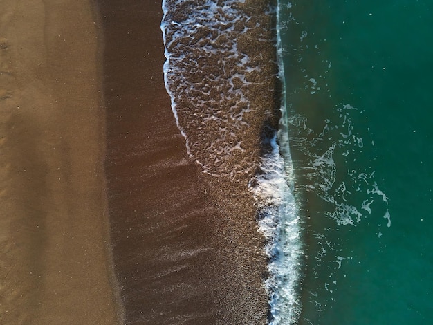 Luchtfoto van zandstrand en zee met golven, bovenaanzicht, geweldige natuurachtergrond, strand en helder water, vliegende drone, uitzicht op zee, kopieer ruimte.