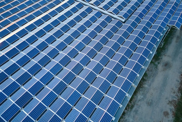 Luchtfoto van zonne-energiecentrale met blauwe fotovoltaïsche panelen gemonteerd op het dak van een industrieel gebouw voor het produceren van groene ecologische elektriciteit Productie van duurzaam energieconcept