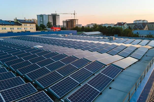 Luchtfoto van zonne-energiecentrale met blauwe fotovoltaïsche panelen gemonteerd op het dak van een industrieel gebouw voor het produceren van groene ecologische elektriciteit productie van duurzaam energieconcept