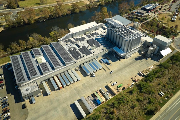 Foto luchtfoto van zonne-energiecentrale met blauwe fotovoltaïsche panelen gemonteerd op het dak van een industrieel gebouw voor het produceren van groene ecologische elektriciteit productie van duurzaam energieconcept