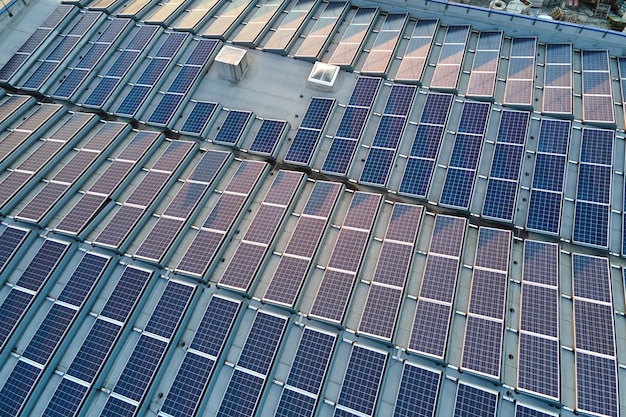 Luchtfoto van zonne-energiecentrale met blauwe fotovoltaïsche panelen gemonteerd op het dak van een industrieel gebouw voor het produceren van groene ecologische elektriciteit Productie van duurzaam energieconcept