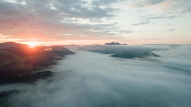 Luchtfoto. van zonsondergang of zonsopgang en mist in de vallei tussen de bergen.