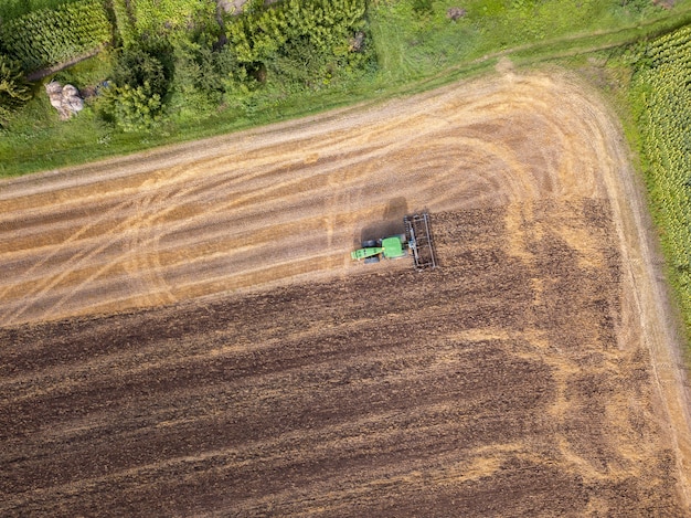 Luchtfoto vanaf de drone van het veld na de oogst. De tractor ploegt het veld en bereidt de grond voor op landbouwwerkzaamheden.
