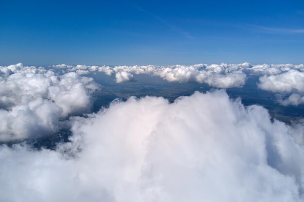 Luchtfoto vanuit het vliegtuigraam op grote hoogte van de aarde bedekt met gezwollen cumuluswolken die zich vormen vóór een regenbui.