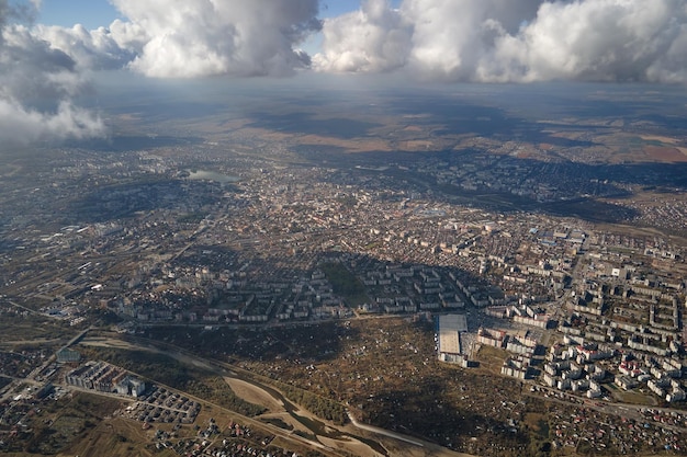 Luchtfoto vanuit het vliegtuigraam op grote hoogte van een verre stad bedekt met gezwollen cumuluswolken die zich vormen vóór een regenbui