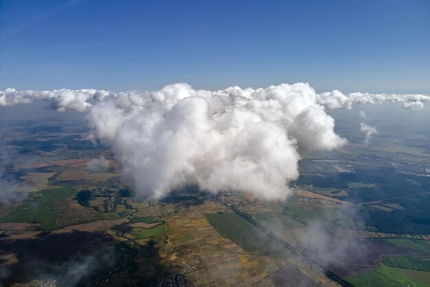 Luchtfoto vanuit vliegtuigraam op grote hoogte van de aarde bedekt met witte gezwollen cumuluswolken.