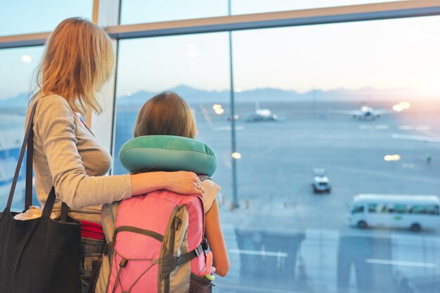 Luchthaven passagiers familie moeder en dochter kind kijken naar vliegtuigen in panoramisch raam