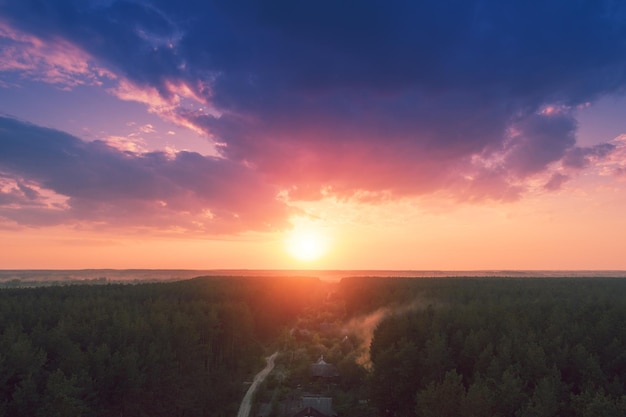 Luchthommelmening van plattelandslandschap met bewolkte hemel bij zonsondergang