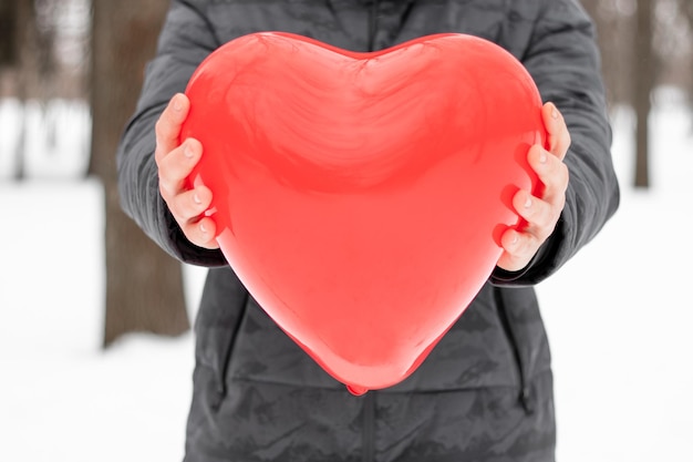 Luchtig rood ballonhart in handen Cadeau voor Valentijnsdag Handen met rood hart gezondheidszorg